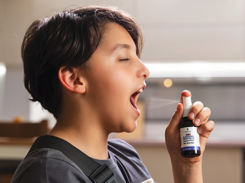 alt="Child spraying BEE&YOU Kids Propolis throat spray into their mouth at home."